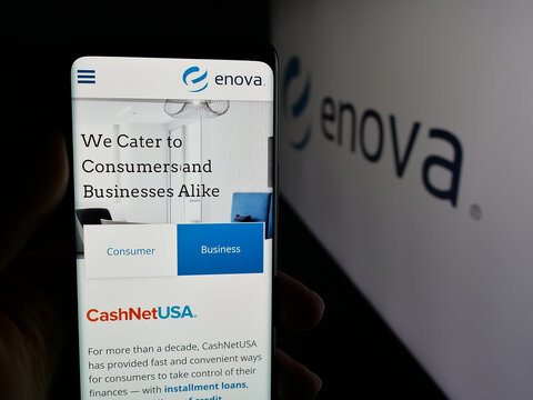 Stuttgart, Germany - 12-10-2025: Person holding smartphone with web page of US financial company Enova International Inc. on screen in front of logo. Focus on center of phone display.