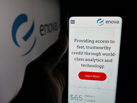 Stuttgart, Germany - 12-10-2025: Person holding cellphone with webpage of US financial company Enova International Inc. on screen in front of logo. Focus on center of phone display.
