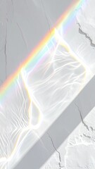 Sunlight refracted through water creating a vibrant rainbow and caustic patterns on a textured white wall.