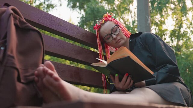 leisurely individual with vibrant braids, casual person resting amidst sunlight and greenery, tranquil moment capturing carefree individual relaxing on bench amid luscious foliage and bright colors