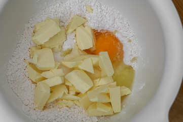 Egg, butter and flour, ingredients for shortcrust pastry in a bowl