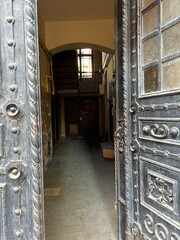 Historic Courtyard Seen Through Ornate Metal Door in Poland.
View into an old courtyard through an ornate metal door, historic architecture and moody interior.