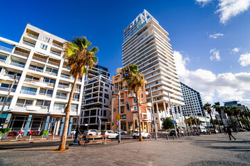 Seaside promenade with people in a luxury district with contemporary architecture in Tel Aviv, Israel.