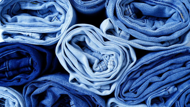 Rolled jeans background in dark and light blue. Texture background of close-up denim jeans. Creative, classic, fabric, fashion, wear style for wallpaper, garment backdrop. Stacked of navy blue denim.