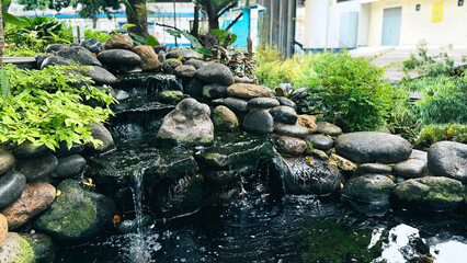 Outdoor Landscape Design Featuring Artificial Stone Waterfall and Fish Pond © fahryfd