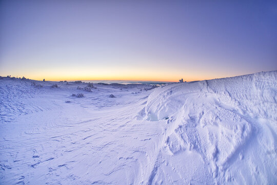 View of a snow-covered landscape bathed in the cool hues of twilight, where crisp textures meet the soft glow of the horizon, Kosarisko, Banska Bystrica region, Slovakia.