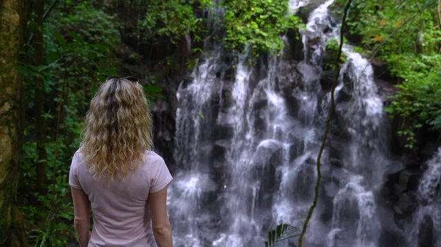 Blonde Tourist Woman Visiting Kanto Lampo Waterfall Cascades In Bali, Indonesia