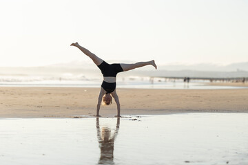 Young woman performing cartwheel on beach at sunset