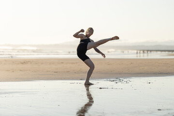 Woman performing capoeira kick on a sandy beach