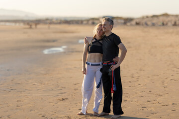 Capoeira couple standing together on sandy beach