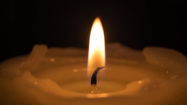 Close up of a lit candle flame on black background - Powered by Adobe