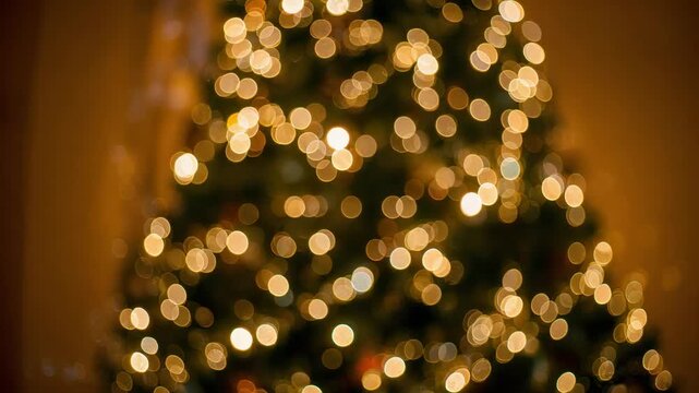 Showing decorated evergreen tree with twinkling bokeh as camera refocusing in home, warm lights