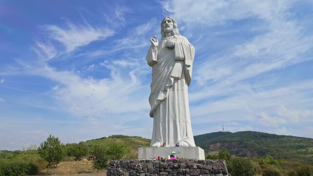 A walk around the &Aacute;ld&oacute; Krisztus statue in Tarcal, Hungary, surrounded by scenic hills, greenery, and a clear sky, showcases its spiritual significance and serene natural setting.
