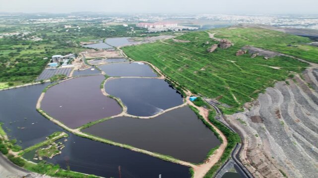 Farming lands with water ponds and urban dumpyard at balaji nagar, hyderabad, india. day time, semi circle shot, drone shot, 4k.