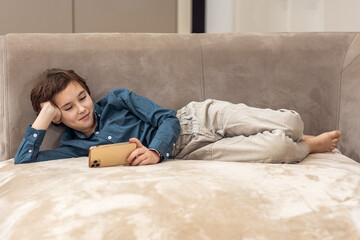 Portrait of a boy relaxing on the couch with a smartphone