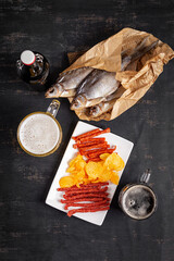 Beer and snack, chips and kabanos on a dark background.
