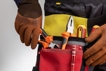 electrician taking plier from tools belt.