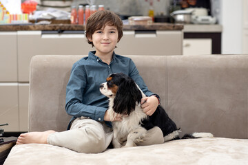 Boy relaxing at home on sofa with his dog