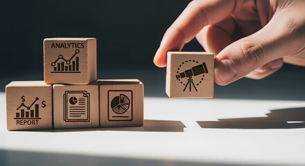 Hand placing wooden block with camera icon on stack of blocks with business graphics