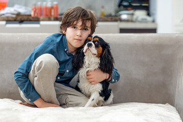 Boy relaxing at home on sofa with his dog