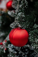 Christmas Ornament close-up: A close-up shot of a vibrant red ornament hanging on a festive Christmas tree, adorned with fresh snow.