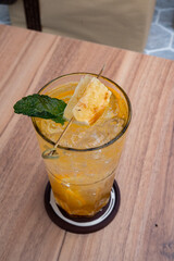 Tropical Elixir: A refreshing cocktail with a slice of pineapple and a sprig of mint, artfully arranged in a glass. This invigorating beverage sits on a wooden table, promising a burst of flavor.