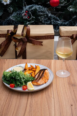 Festive Feast: A beautifully arranged plate featuring grilled salmon, accompanied by vibrant side dishes, a refreshing glass of wine, and wrapped presents, evoking a sense of celebration. 