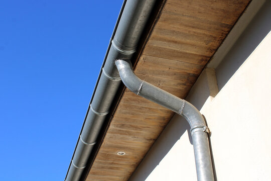 Goutti&egrave;re zinc gris sur la fa&ccedil;ade de la maison, descentes rondes et sous-face en lambris bois	