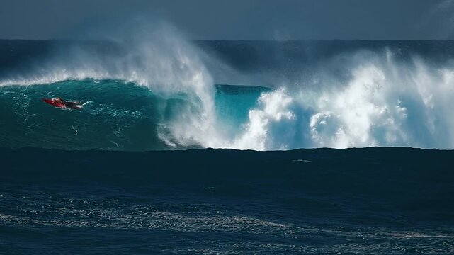 Big wave surfing in Hawaii on Waimea Bay. Person surfs the huge ocean wave breaking on the Hawaiian shore in Waimea Bay. Surfer rides the big wave in Hawaii. Oahu island