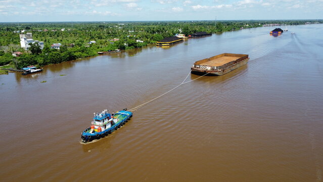 Aerial view of a tugboat pulling a barge filled with coal in the waters of South Kalimantan, Barito River