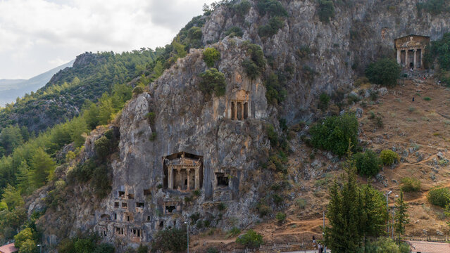 Ancient Lycian rock tombs carved into cliff in Fethiye, Turkey. Historic archaeological landmark surrounded by mountains and nature, popular travel destination.