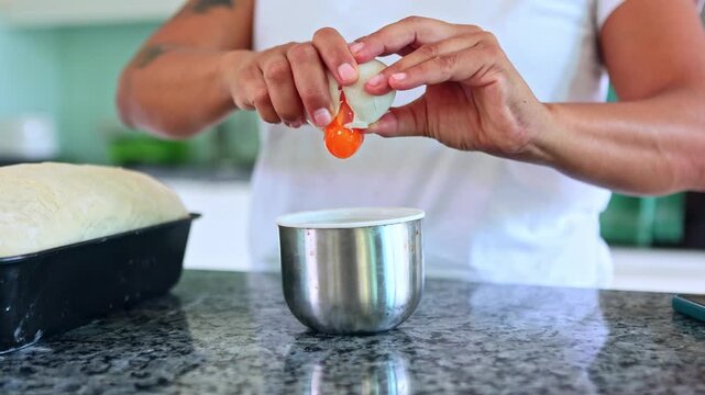 Woman separating egg yolk from white for baking bread