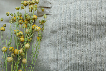Linen clothing in gender-neutral colors with flax stalks featuring golden seed pods. Fabric Linen...