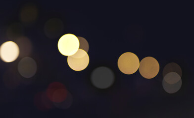 Soft glowing orbs drift across a dark evening backdrop, with warm yellow and amber light spots