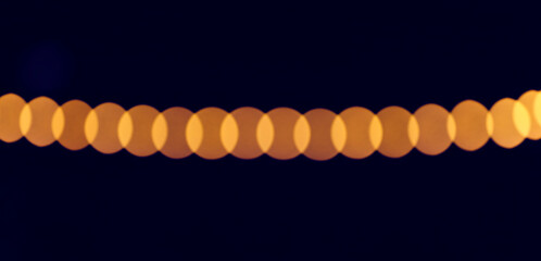 Soft blurred golden lights create a continuous horizontal band of overlapping bokeh circles on a