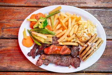 Appetizing combination plate of grilled meat with vegetables and tortillas.