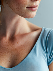 Naklejka premium Portrait of a woman with freckled skin wearing a soft blue top highlighting natural beauty and delicate facial features in soft lighting