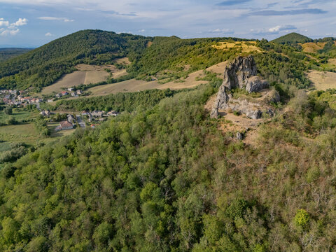 Aerial view of the striking rock formation and lush green forests under a cloudy sky, Hajnacka, Cerova vrchovina, Banska Bystrica Region, Slovakia.