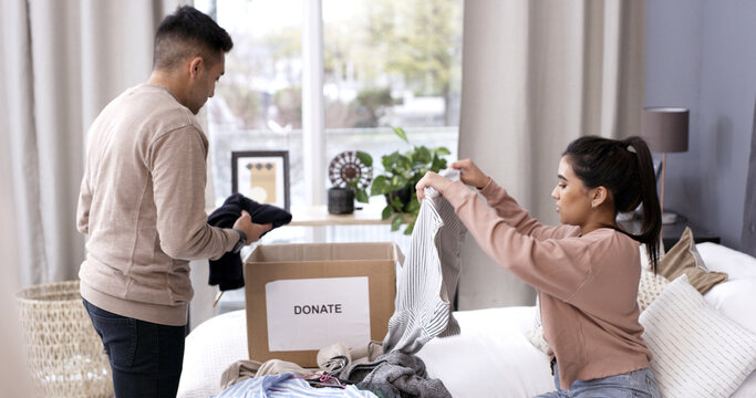 Couple, folding clothes and donation box in home for charity initiative, nonprofit or declutter closet. Married people, apparel and giveaway in package for NGO contribution, support or clean bedroom.