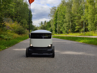 Delivery robot operating on a sidewalk in Espoo, Finland. Six-wheeled zero-emission robot used for last-mile grocery and food delivery