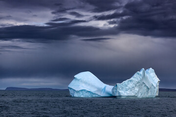 Majestic blue iceberg in the Arctic Ocean. Off the coast of Bontecoe O Island in the Greenland sea. Stormy sky with dark and moody processing.
