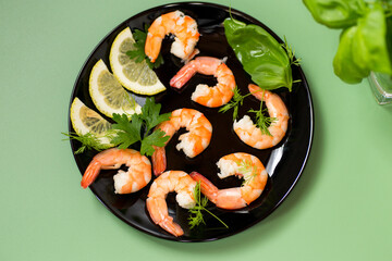 Still life of shrimps with lemon isolated on green background