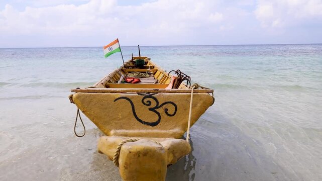 traditional wooden fishing boat with om sing and indian flag in shallow sea