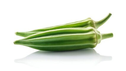 Two vibrant green, ribbed vegetables, possibly pods, lie on a reflective white surface. Their shapes are elongated