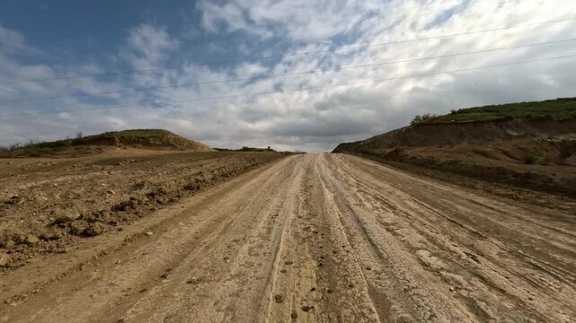 Off-road driving in 4WD vehicles on dirt roads among mountains and hills at high speed. First-person perspective. Shot with an action camera without motion blur.