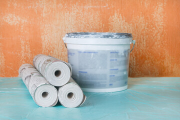 Wallpaper rolls, a brush, and paint on an old wall in a house or apartment. Concept for preparing for renovation