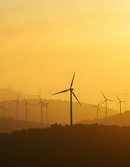 Wind turbines silhouetted against a hazy golden sunset on rolling hills