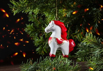 A porcelain Christmas tree ornament in the shape of a small horse on a spruce branch. A still life for the Year of the Horse