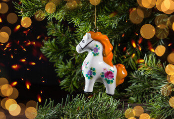 A porcelain Christmas tree ornament in the shape of a small horse on a spruce branch. A still life for the Year of the Horse