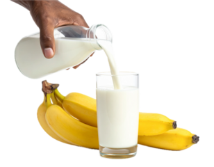 A man hand pouring white creamy milk into long glass of banana milk isolated on white background.